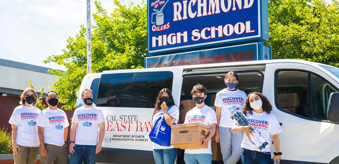 Students stand in front of CSUEB van with boxes