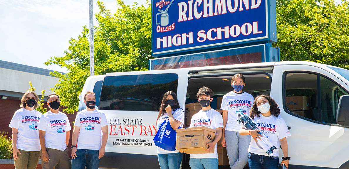 Students stand in front of CSUEB van with boxes