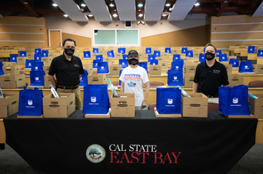 Two professors stand with President Sandeen with prepared boxes