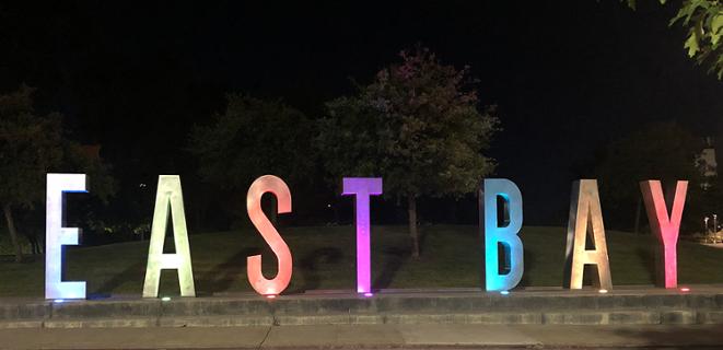 East Bay monument letter lit up in rainbow colors