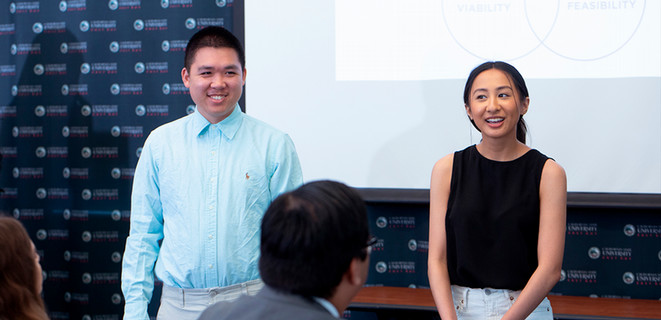 Two business students giving a presentation in front of their peers.