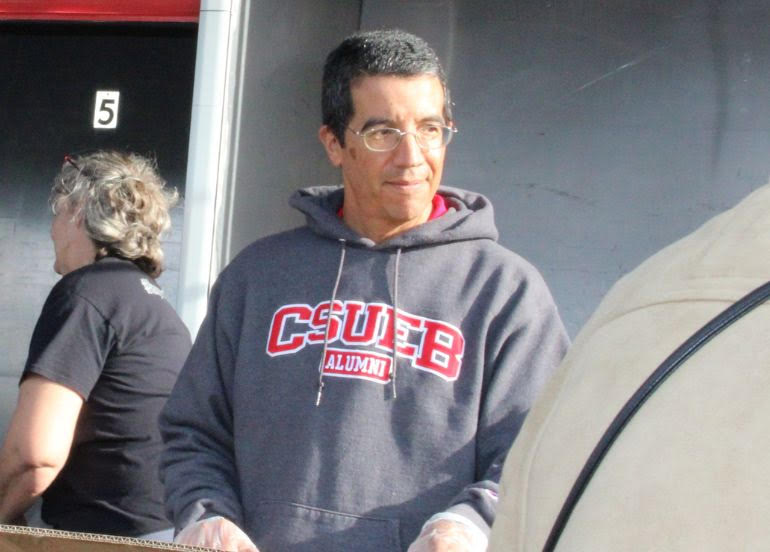 Alumn with a CSUEB sweatshirt distributing food