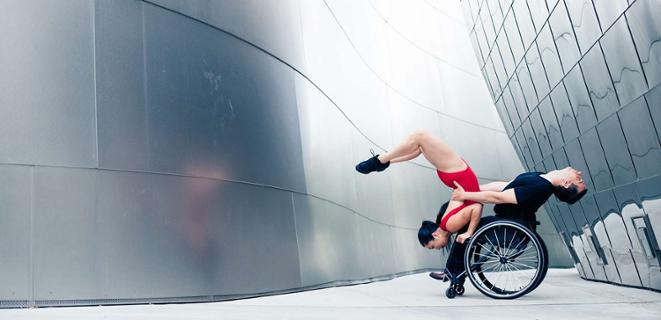 Dancers, one in a wheelchair, the other being held by the person in a wheelchair, perform.