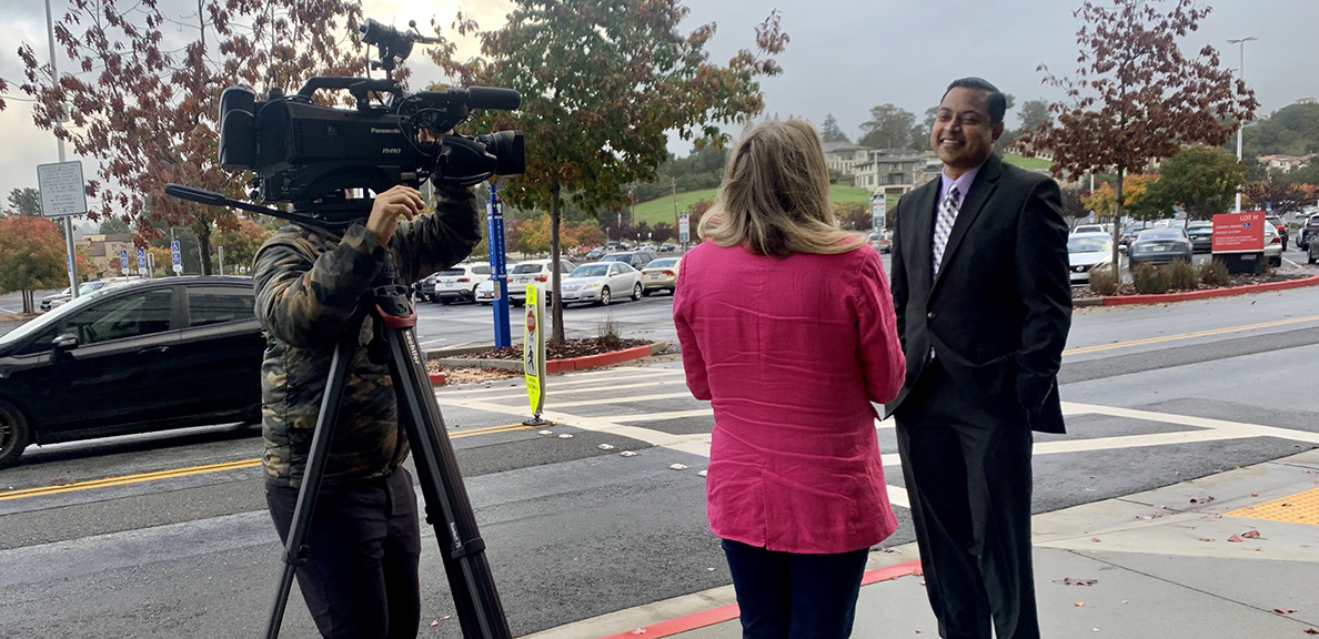 Professor chats with a news crew on campus