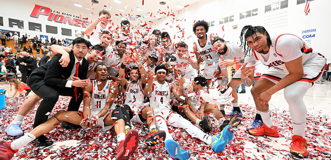 A group photo of the Cal State East Bay's Men Basketball team with red, white, and black confetti inside the Pioneer Gymnasium 