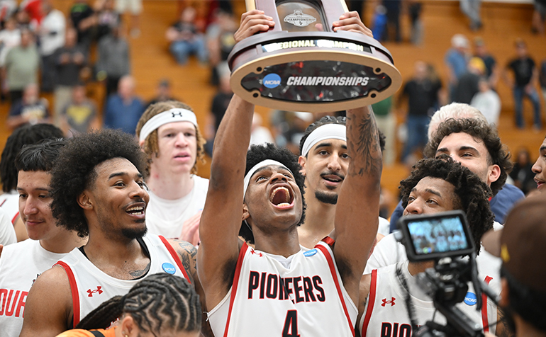 A group photo of the Pioneer Men's Basketball team holding the NCAA II West Regionals championship trophy.
