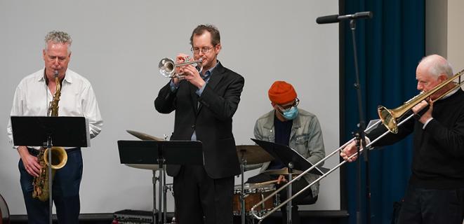 Four musicians play instruments.
