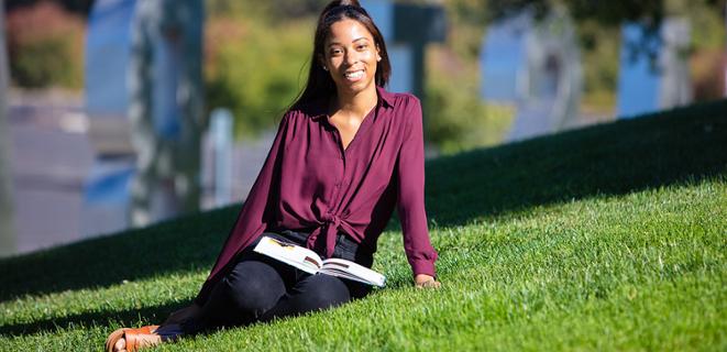 Student sits on grassy hill
