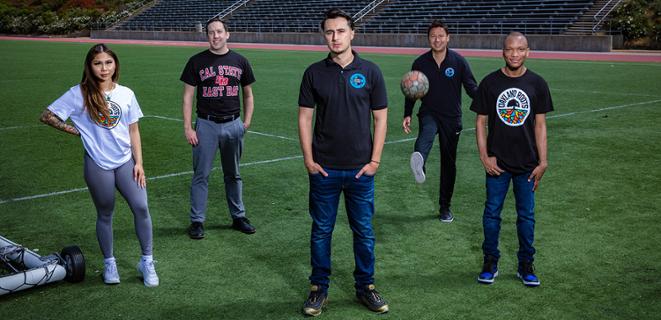 Five people pose on soccer field