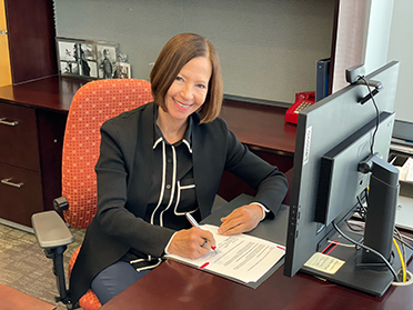 President Sandeen signs paper at her desk.