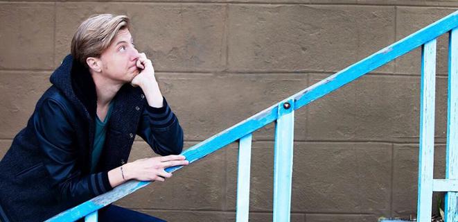 Scott Turner Schofield poses on a blue stairway