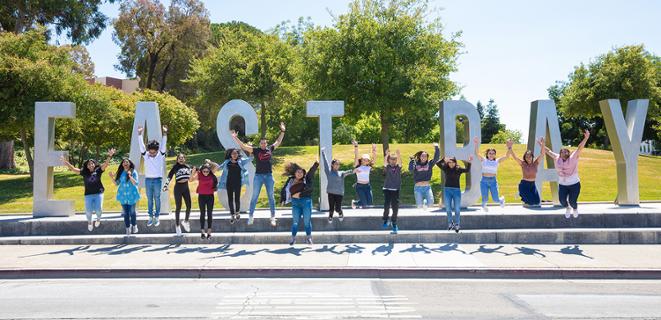 Students jumping in front of East Bay sign