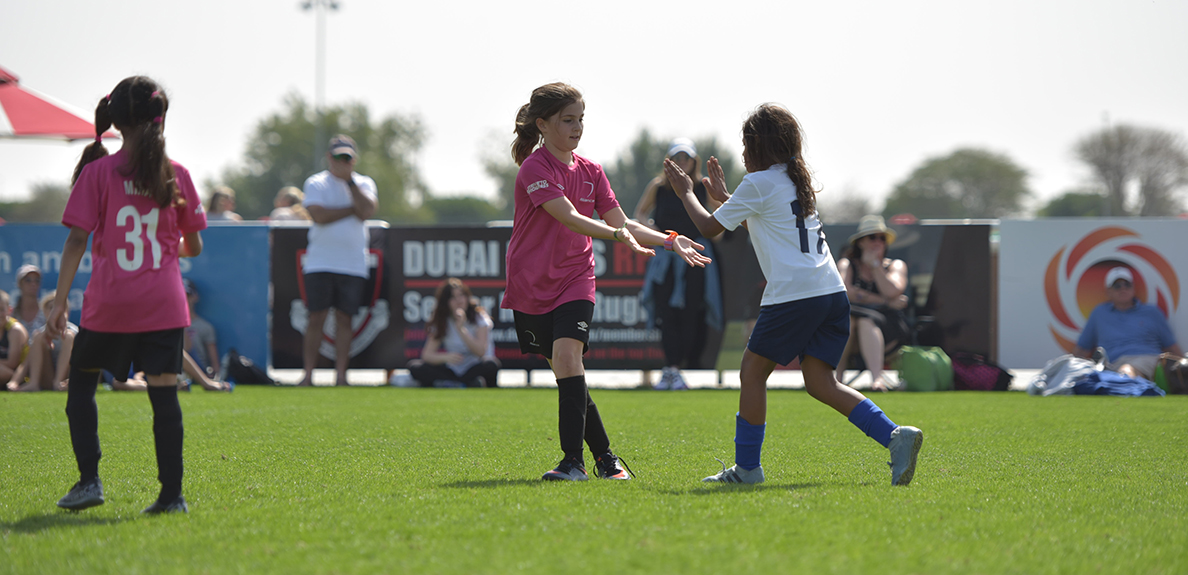 Girls on soccer field high-five