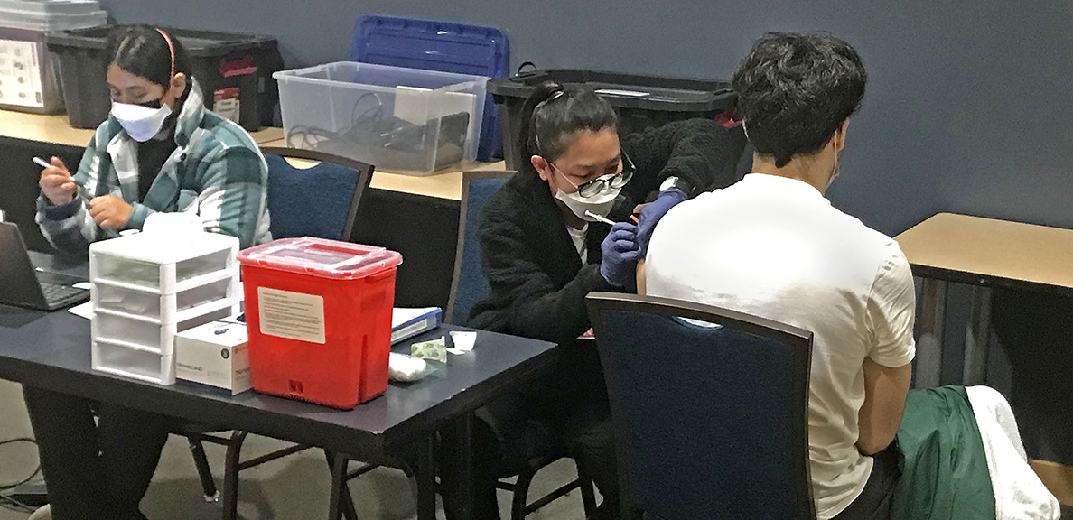 People in masks stand in front of vaccine clinic