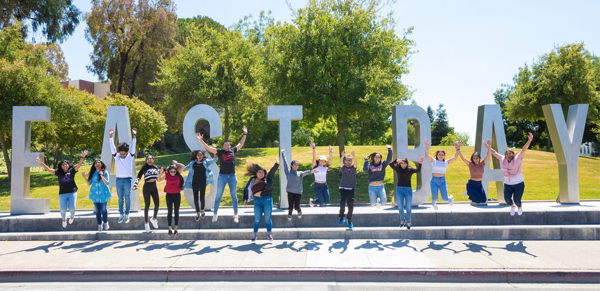 Students jumping in front of East Bay letters