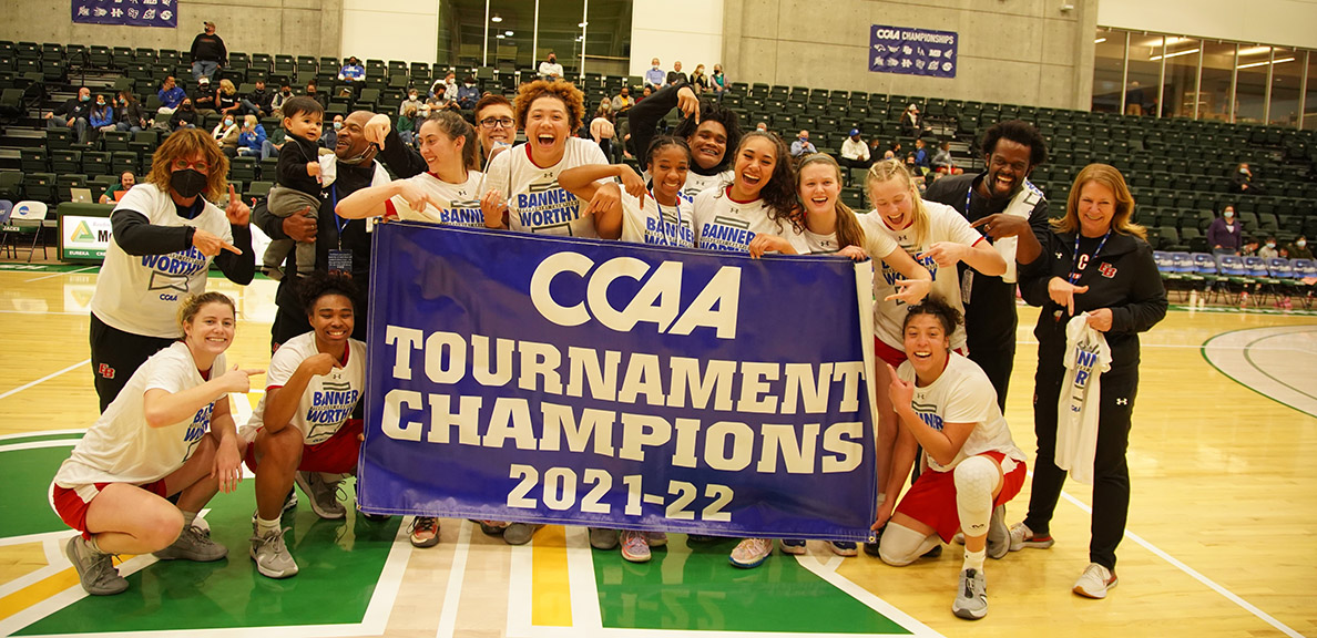 Women's basketball team poses with CCAA championship banner