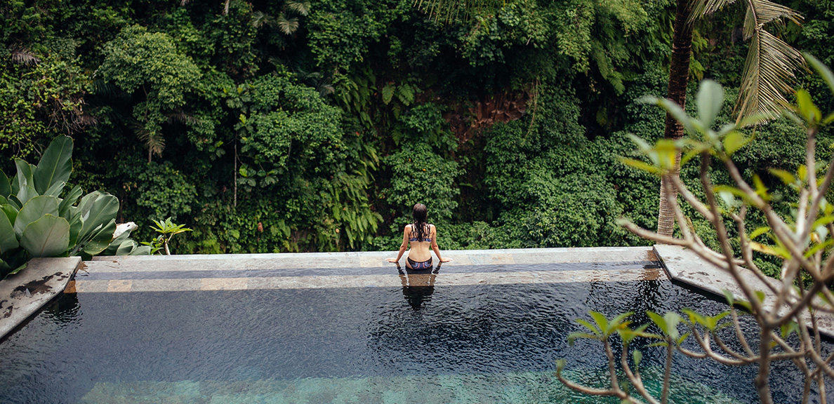 Woman swimming in an infinity pool in a forest retreat