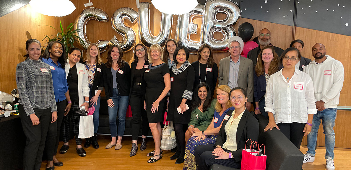Women in leadership mentors posed under balloons that spell CSUEB