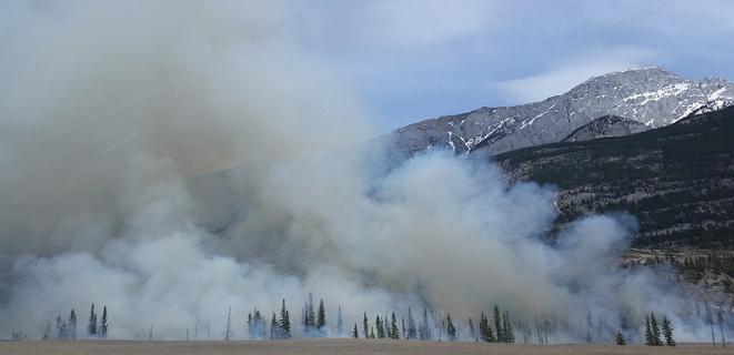 A large amount of smoke drifts over mountains