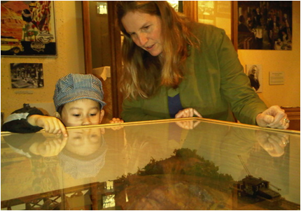 Marjorie Rhodes-Ousley helps Kenji, 4, look at a model railroad display. by: Kristofer Noceda