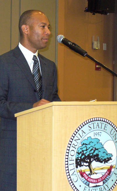 Ken McNeely at podium with CSUEB seal