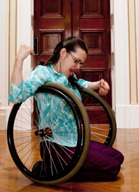 Woman on floor with wheelchair, in front of closed door.