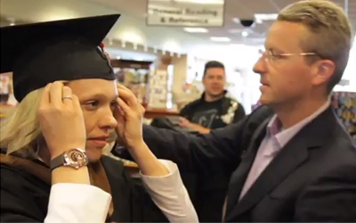 blonde woman puts on graduation cap and gown