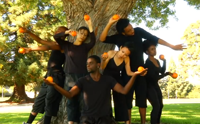 People in dance stances holding persimmons.