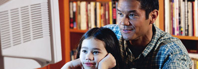 A father and girl look at a computer screen.