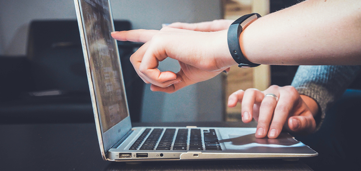 Two people's hands pointing and typing on a laptop. Photo by John Schnobrich on Unsplash.