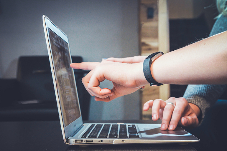 Two people's hands pointing and typing on a laptop. Photo by John Schnobrich on Unsplash.