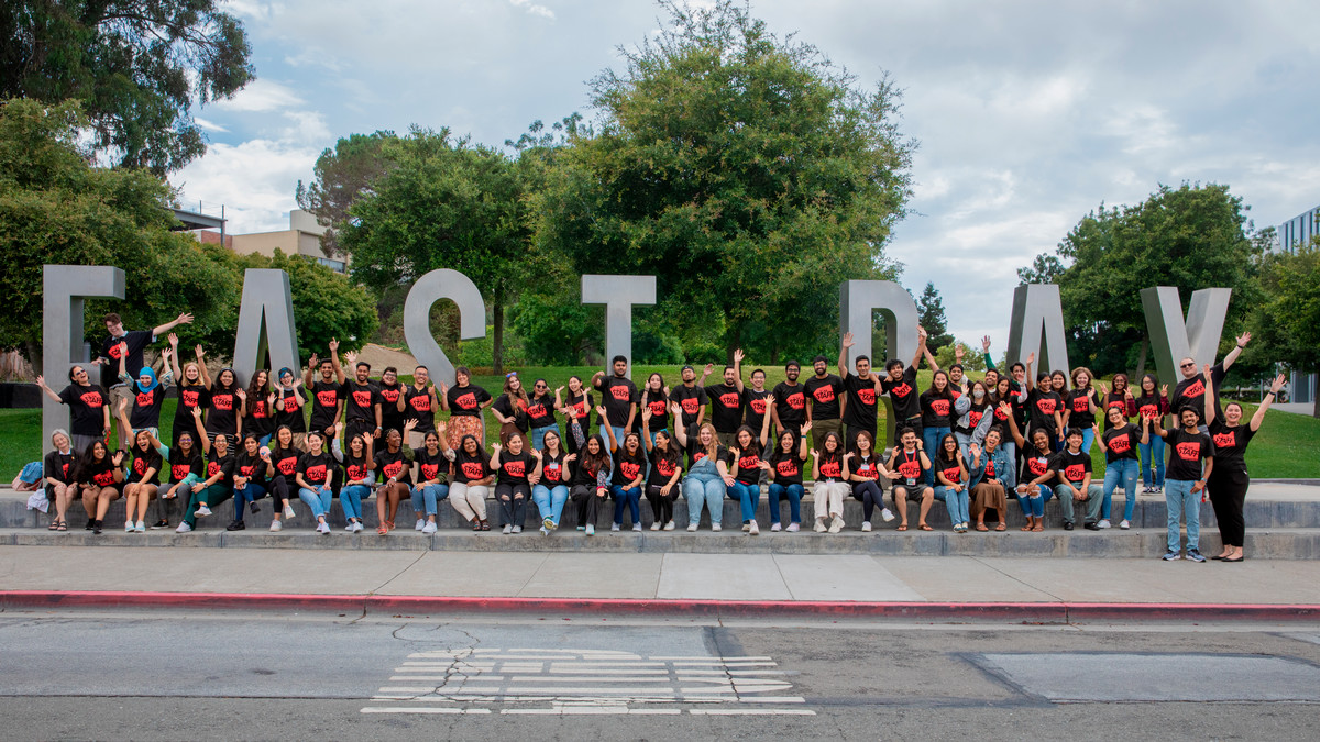 A group of SCAA employees in front of the East Bay monument letters on campus