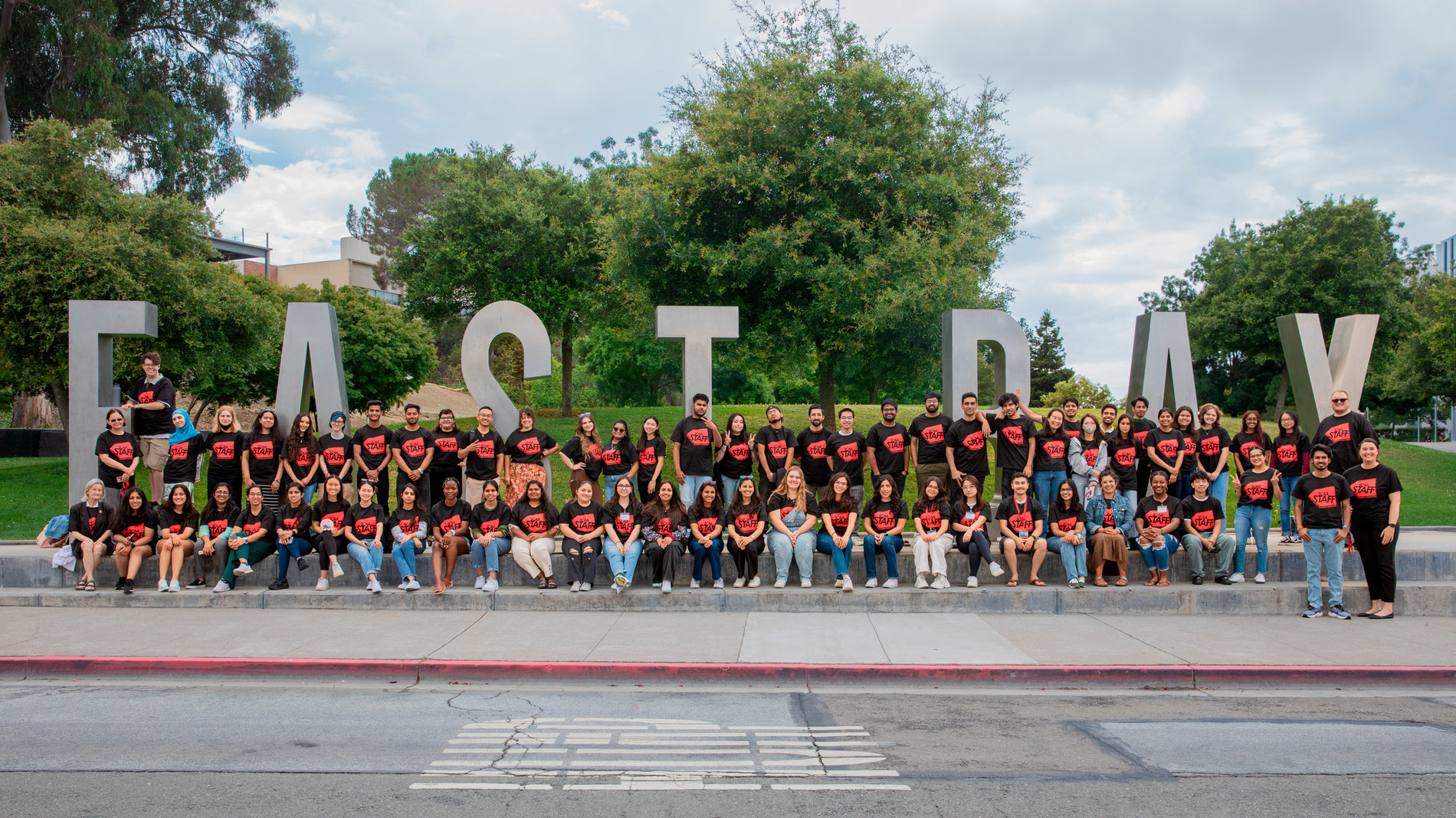 A group of SCAA employees in front of the East Bay monument letters on campus