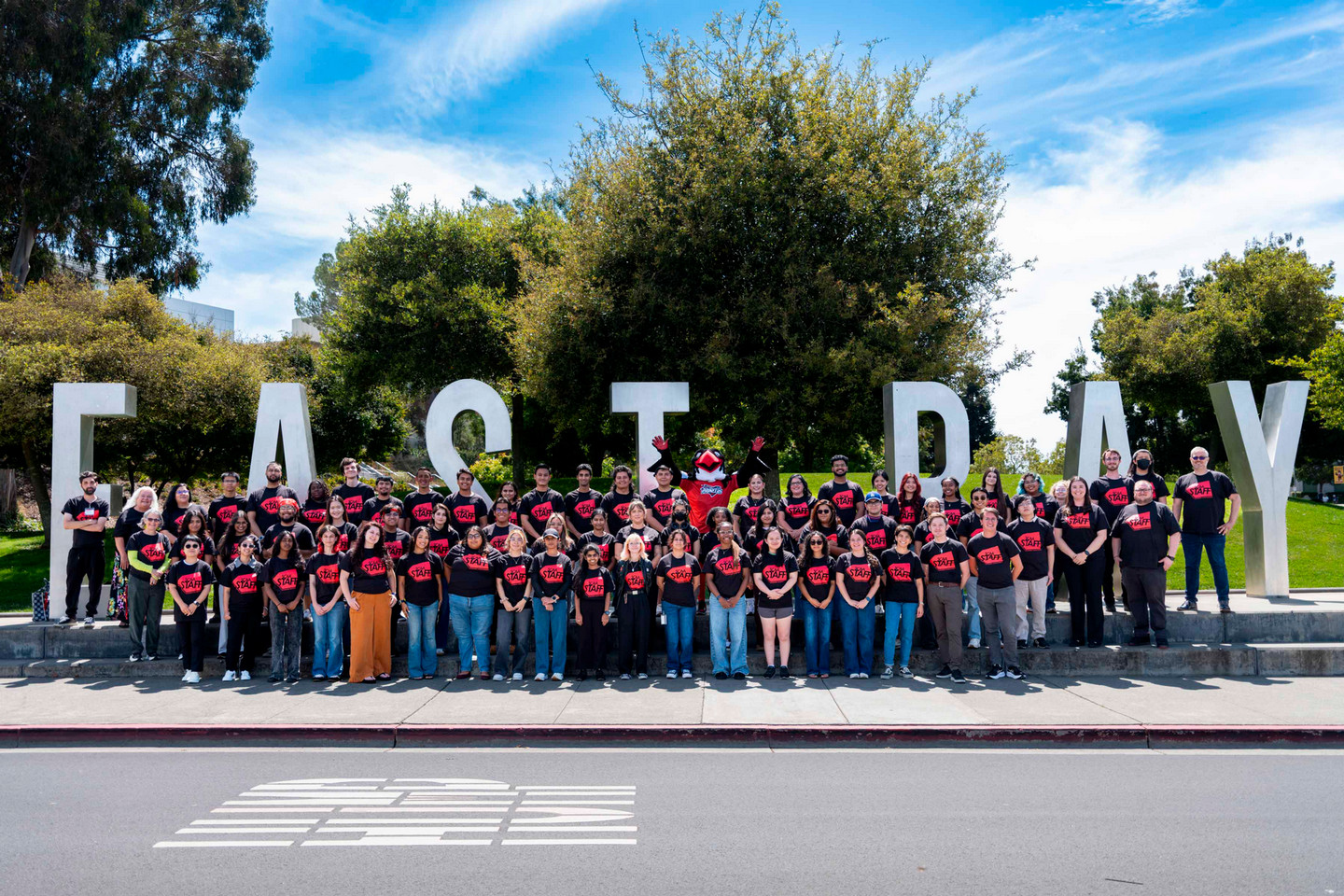 A group of SCAA employees in front of the East Bay monument letters on campus