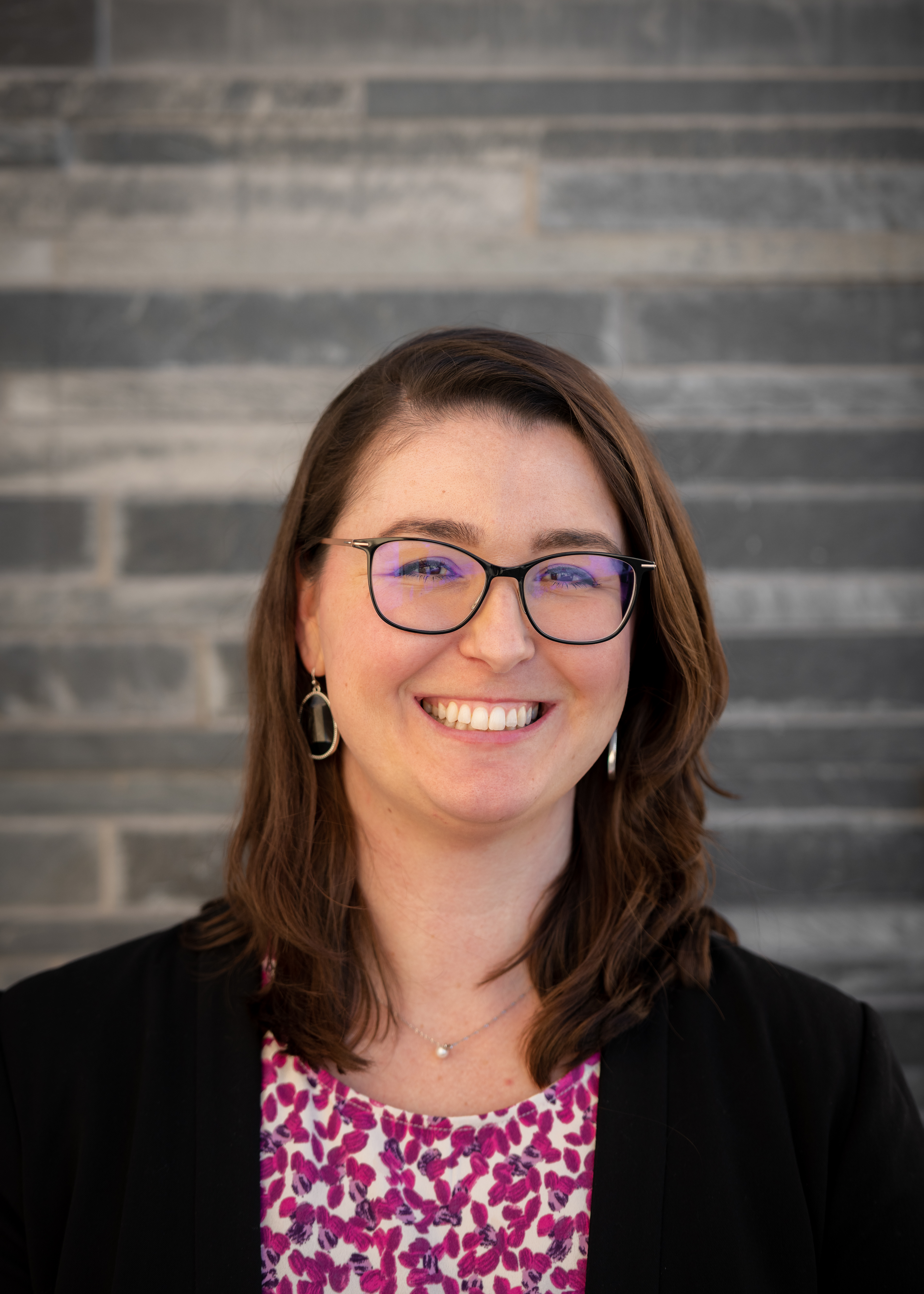 This is a photo of the SCAA Director Rachel against a grey stone wall.