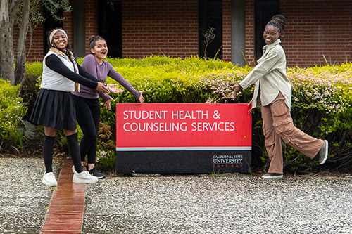 Students outside the SHCS building standing next to the entrance sign