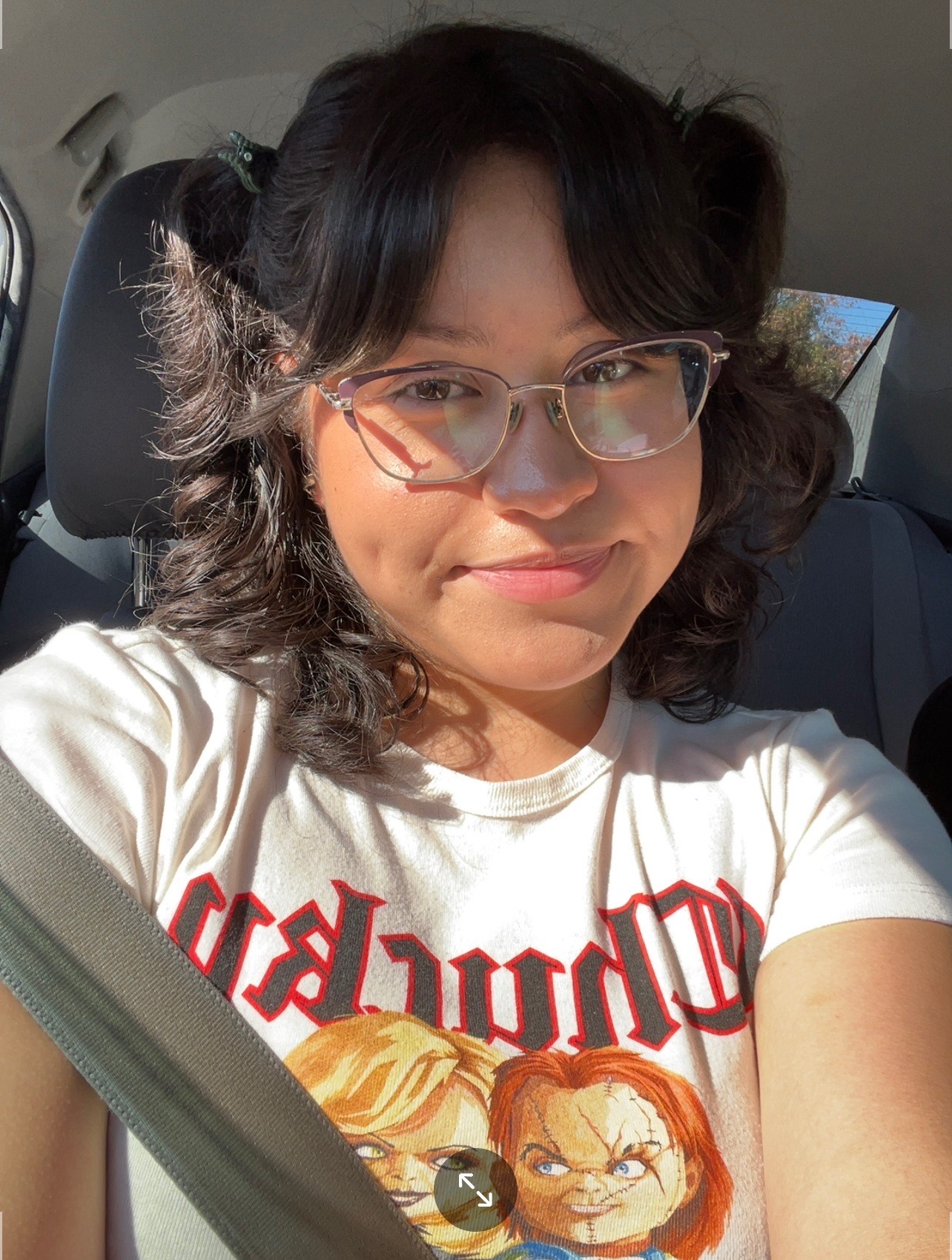 Picture of Leslie, dark-haired Hispanic female with glasses, sitting in her car.