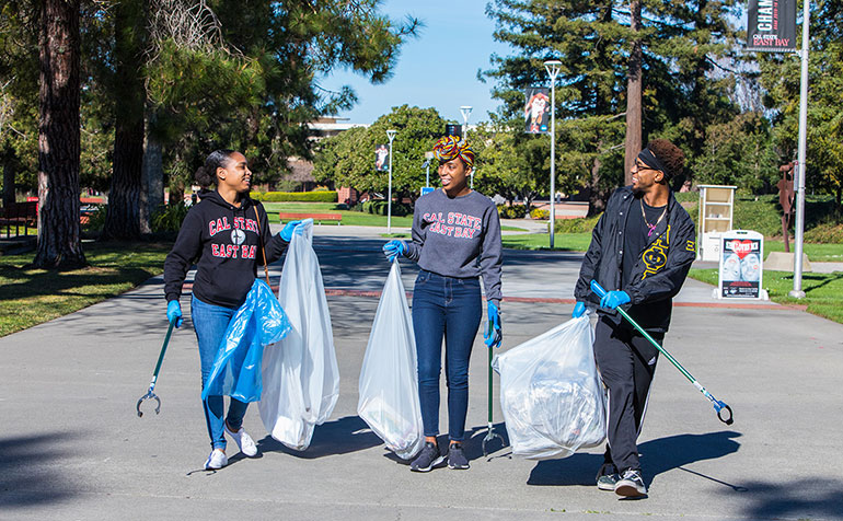 three students at campus clean up
