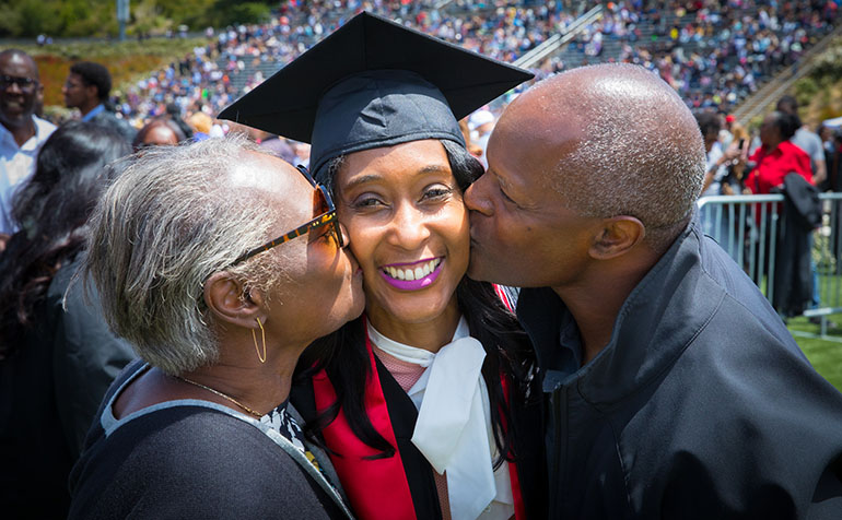Parents kiss graduate on each cheek