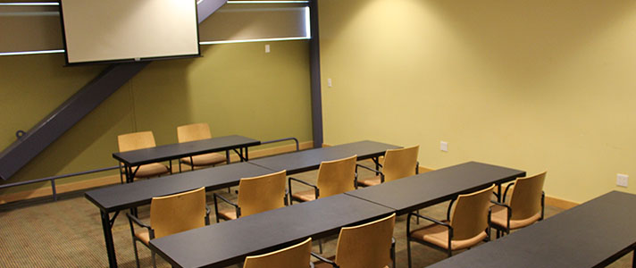 Hayward Room with Tables in Rows with Chairs on One Side and a front Table Facing the Back