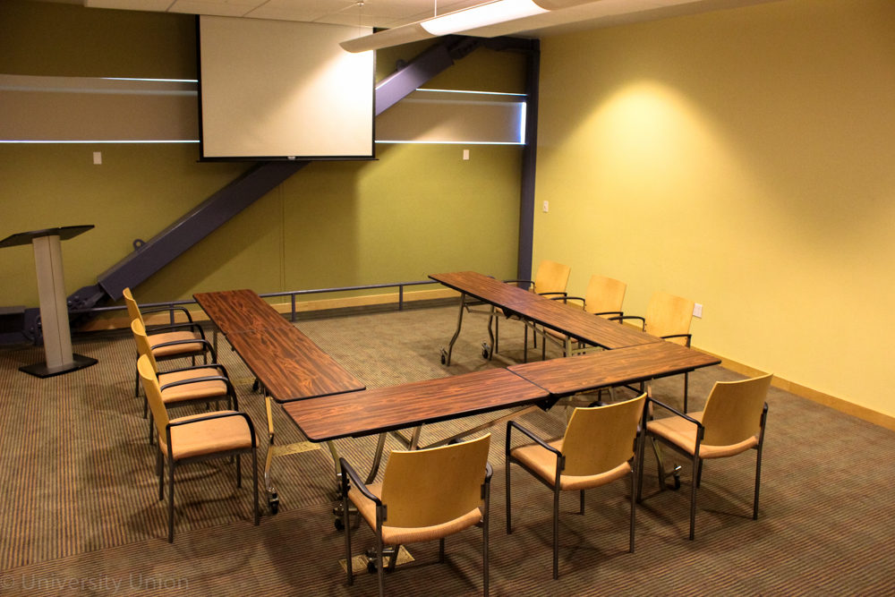 U-Shaped Table with Chairs on the Outside with Podium and Projector Screen in the Front