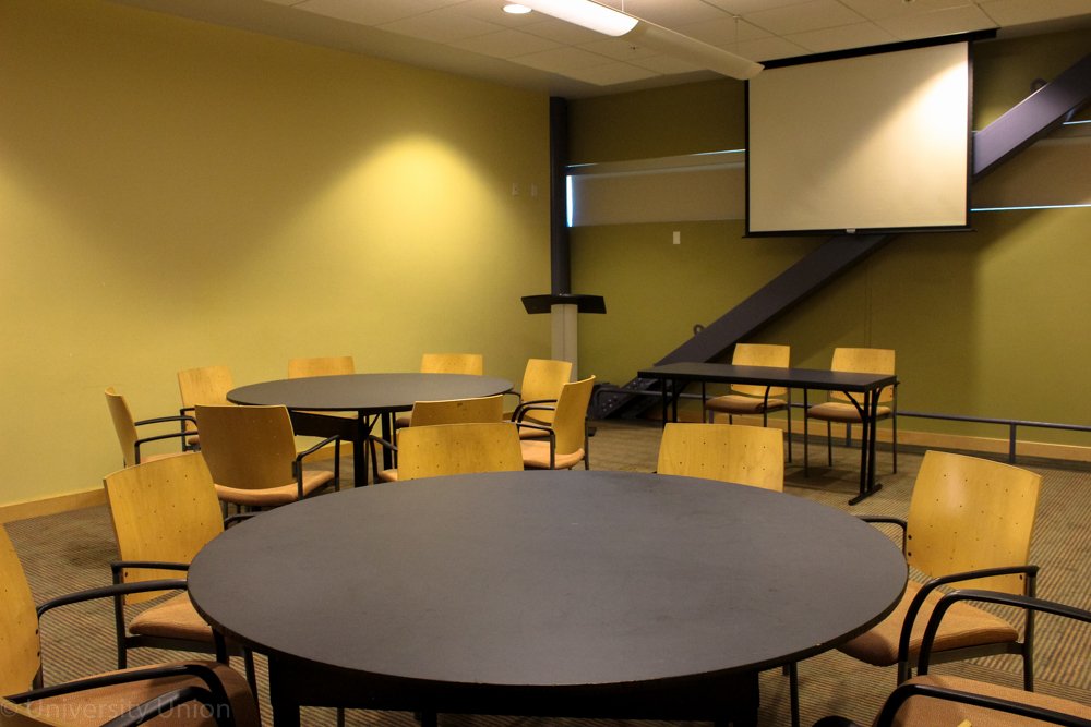 Circular Tables with Chairs with a Podium and Projector Screen in the Front