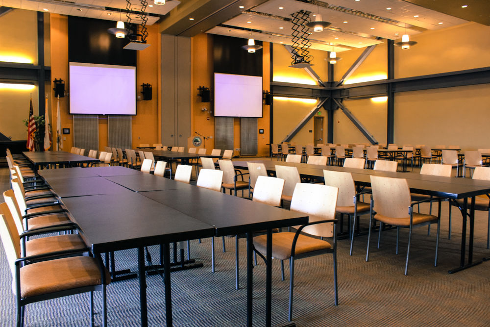 Multiple Rows of Long Rectangle Tables with Chairs on the Outside and a Podium in the Front