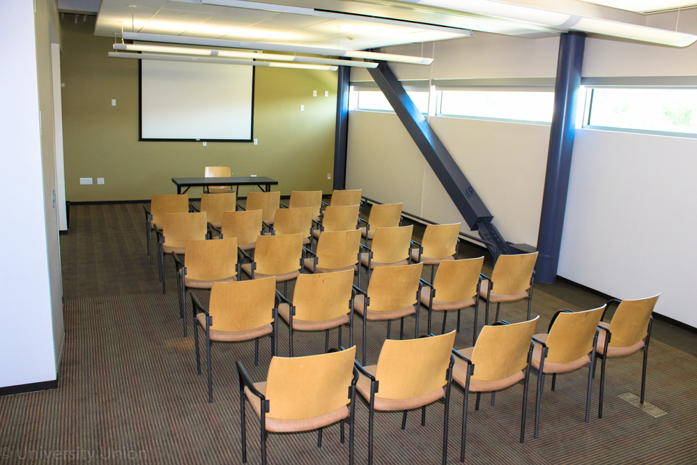 Chairs in Rows Facing Forward and a Table in the Front Facing the Back