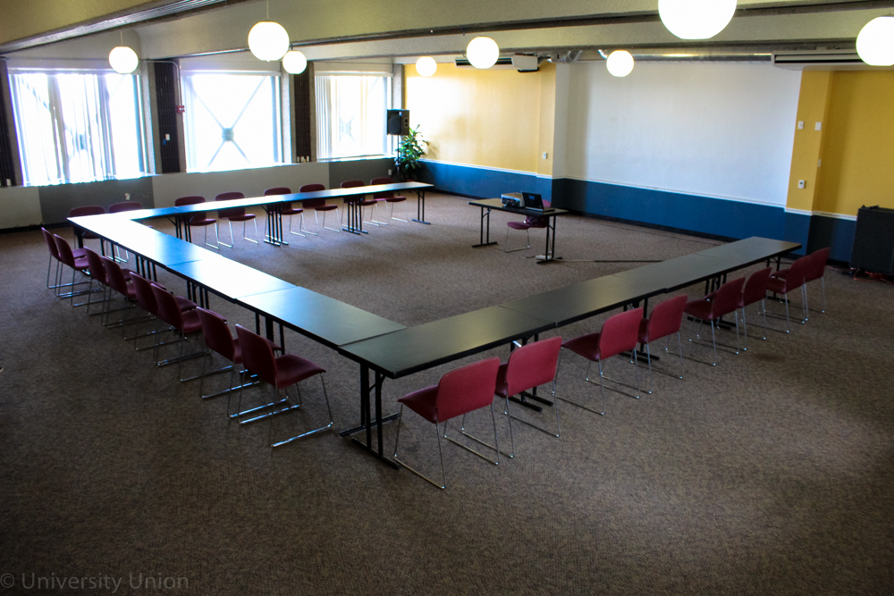 U-Shaped Table with Chairs on the Outside and a Table With Projector in Front
