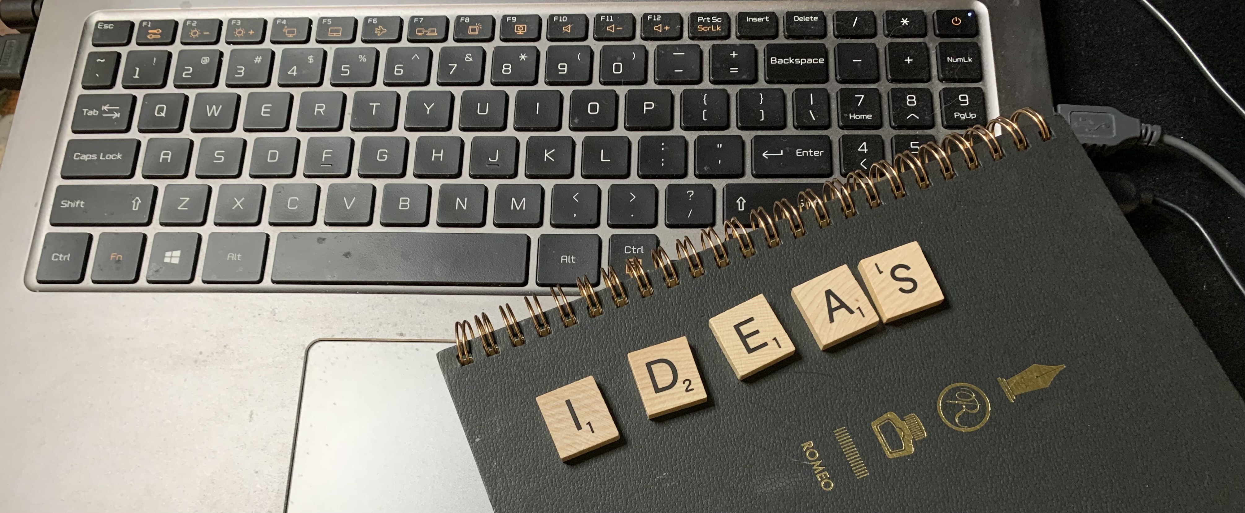 Computer keyboard, notebook and Scrabble letters spelling the word IDEAS